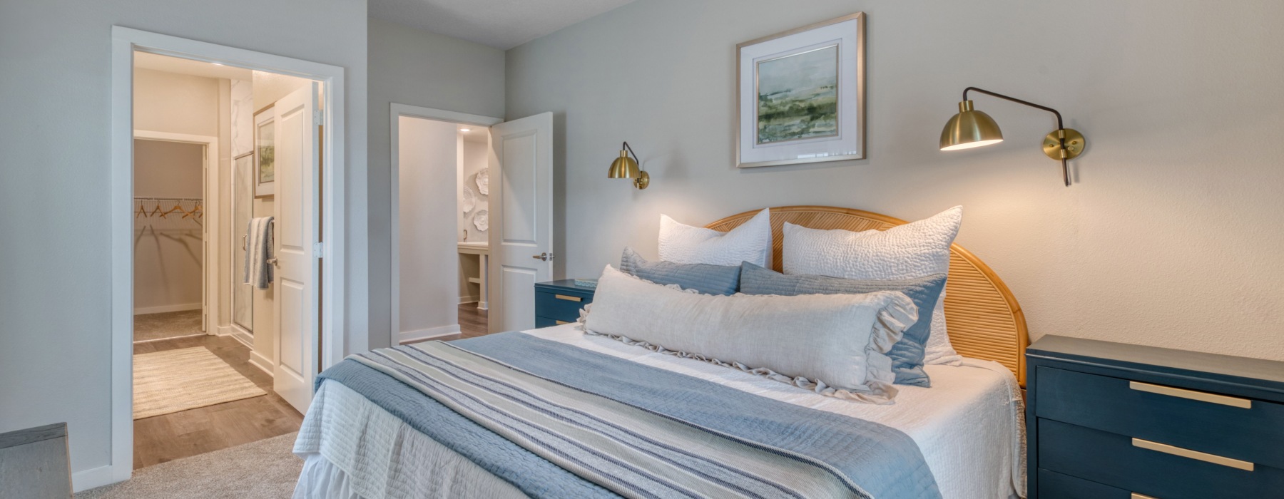 a bedroom with dresser, wall mounted lights, and doors leading to bathroom and hallway